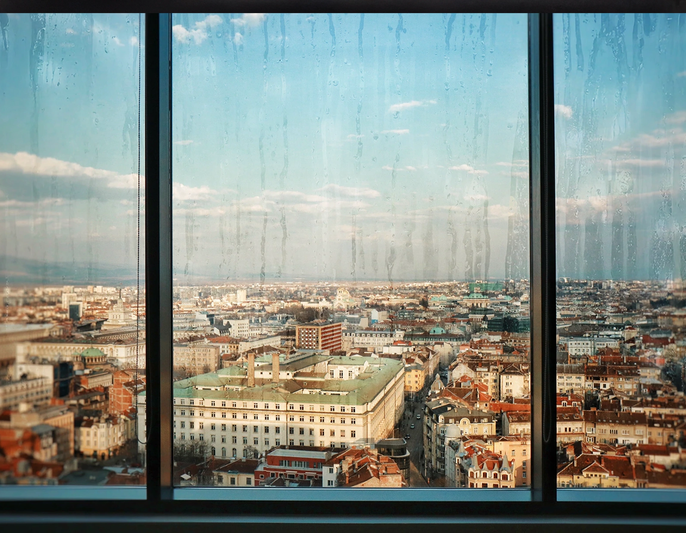 dreckige fensterscheibe mit blick über die stadt, soll den zustand vor dem reinigung darstelln